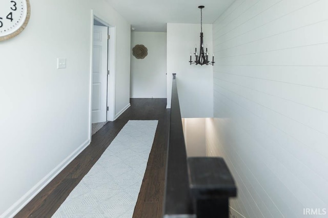 hallway with an inviting chandelier and dark wood-type flooring