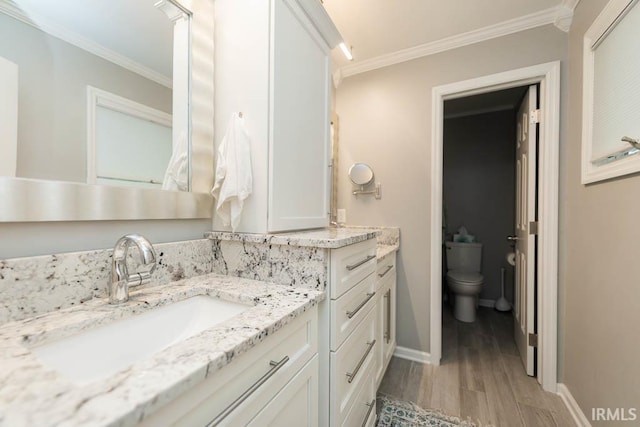 bathroom with wood-type flooring, vanity, toilet, and crown molding