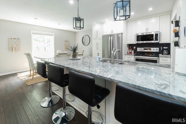 kitchen featuring pendant lighting, a kitchen breakfast bar, sink, white cabinetry, and stainless steel appliances