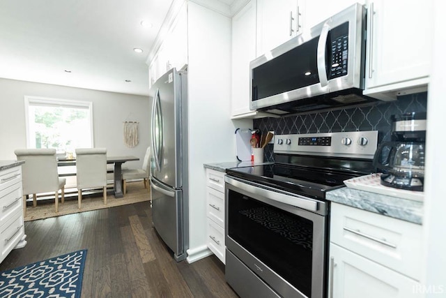 kitchen with decorative backsplash, white cabinets, dark wood-type flooring, and appliances with stainless steel finishes