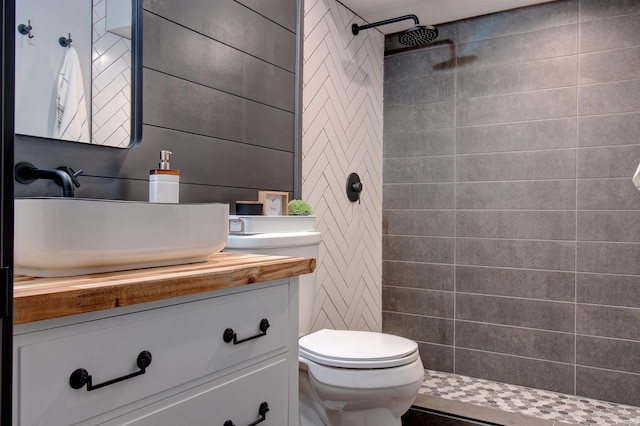 bathroom featuring a tile shower, vanity, and toilet