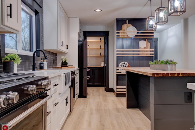 kitchen with black appliances, light hardwood / wood-style flooring, tasteful backsplash, decorative light fixtures, and white cabinetry