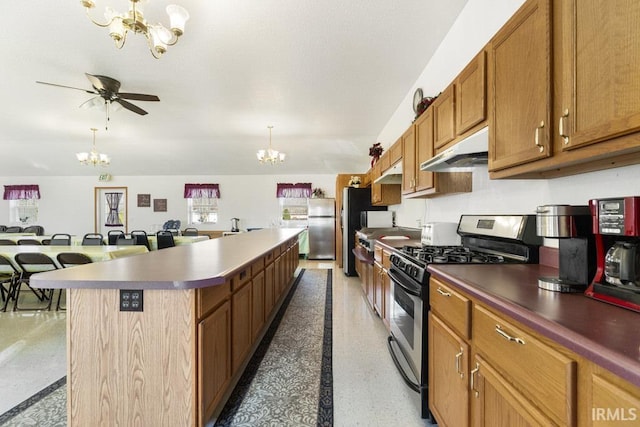 kitchen featuring a center island, ceiling fan with notable chandelier, a kitchen breakfast bar, hanging light fixtures, and stainless steel appliances