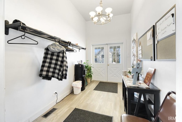 mudroom featuring french doors, light hardwood / wood-style floors, and an inviting chandelier