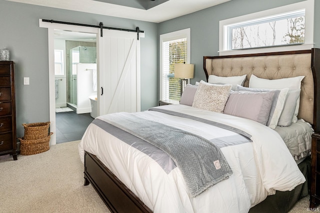 bedroom featuring a barn door, ensuite bathroom, and carpet floors