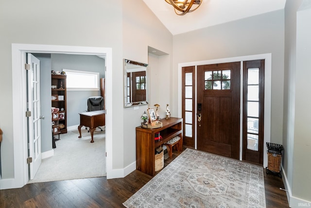 foyer entrance with dark wood-type flooring and vaulted ceiling