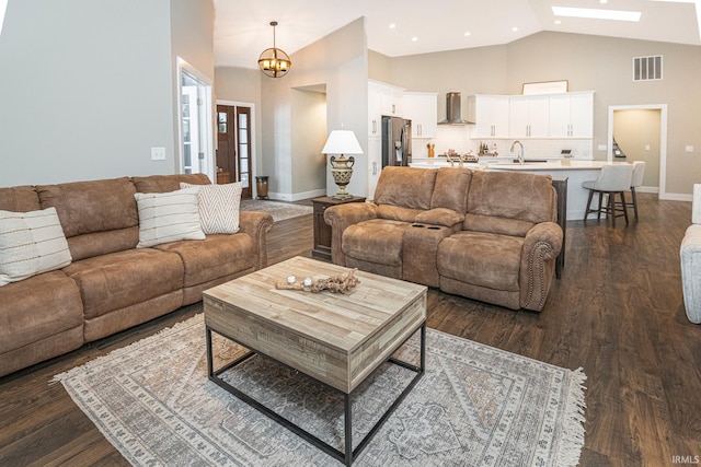 living room with a notable chandelier, sink, lofted ceiling, and dark wood-type flooring