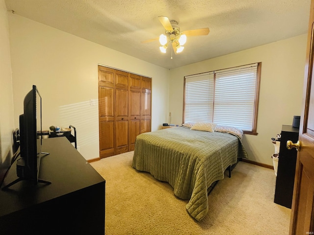 bedroom featuring light carpet, a textured ceiling, a closet, and ceiling fan