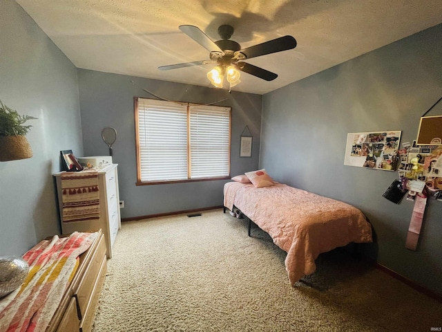 carpeted bedroom featuring ceiling fan and a textured ceiling