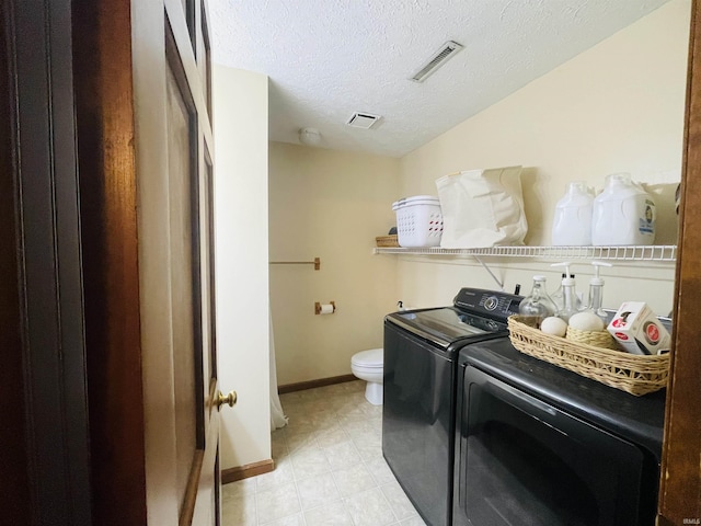 washroom with washing machine and clothes dryer and a textured ceiling