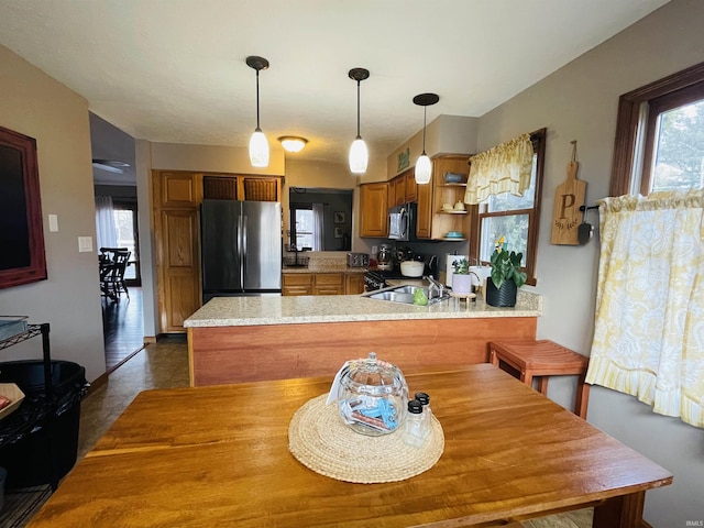 kitchen with stainless steel fridge, kitchen peninsula, sink, and gas range