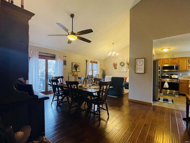 dining space with ceiling fan with notable chandelier, dark hardwood / wood-style floors, and vaulted ceiling