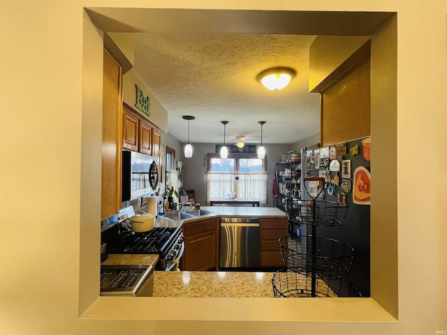 kitchen featuring kitchen peninsula, a textured ceiling, stainless steel appliances, sink, and hanging light fixtures