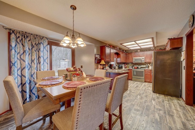 dining space with light hardwood / wood-style floors, a textured ceiling, and a chandelier