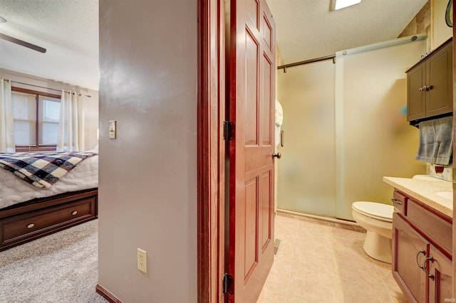 bathroom featuring vanity, ceiling fan, toilet, a textured ceiling, and a shower with shower door