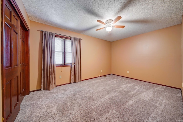 carpeted spare room featuring a textured ceiling and ceiling fan