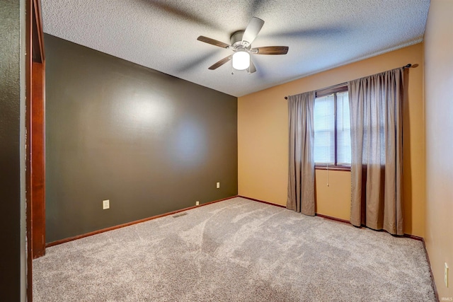 empty room featuring light carpet, ceiling fan, and a textured ceiling