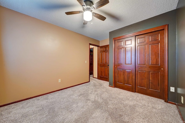 unfurnished bedroom with ceiling fan, a closet, light carpet, and a textured ceiling