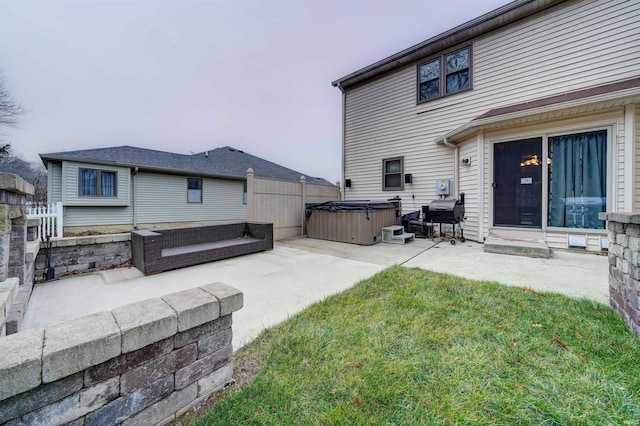 back of house with a lawn, a patio, and a hot tub