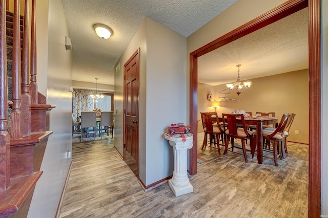 hall with wood-type flooring and an inviting chandelier