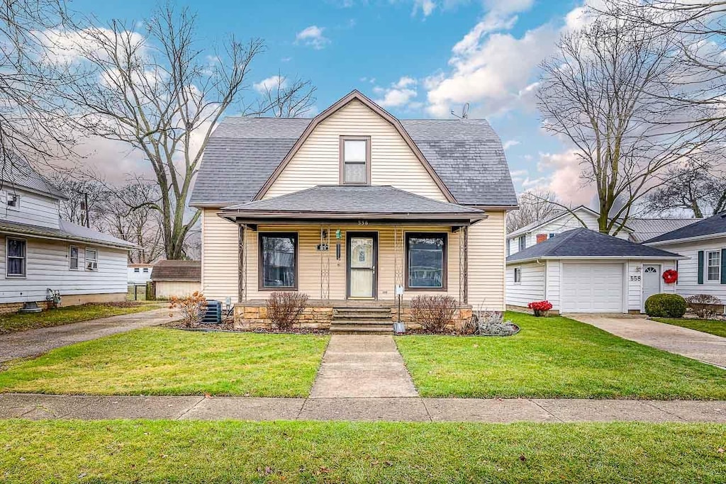 bungalow-style house with a porch, a garage, and a front lawn