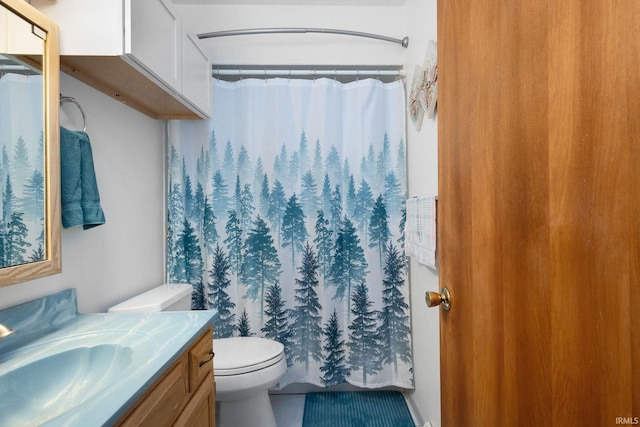 bathroom with walk in shower, vanity, and toilet