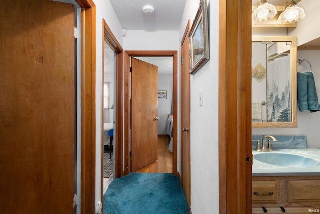 corridor with light hardwood / wood-style floors and sink