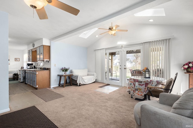 living room featuring french doors, light colored carpet, ceiling fan, and vaulted ceiling with skylight