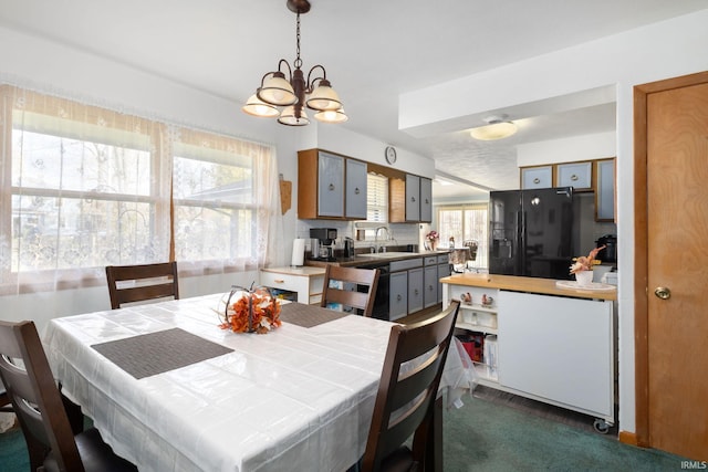 dining space with sink, a chandelier, and dark colored carpet