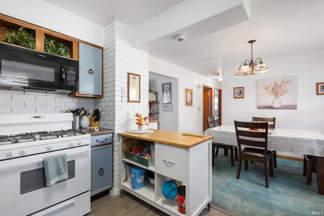 kitchen featuring dark hardwood / wood-style flooring, white gas range oven, backsplash, a chandelier, and hanging light fixtures