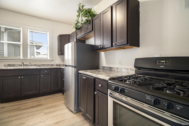 kitchen featuring dark brown cabinetry, sink, stainless steel appliances, and light hardwood / wood-style floors