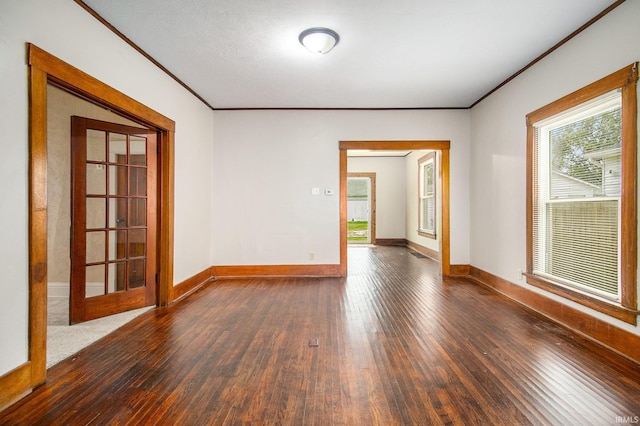 empty room featuring dark hardwood / wood-style flooring, ornamental molding, and french doors