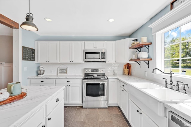 kitchen with white cabinetry, sink, pendant lighting, decorative backsplash, and appliances with stainless steel finishes