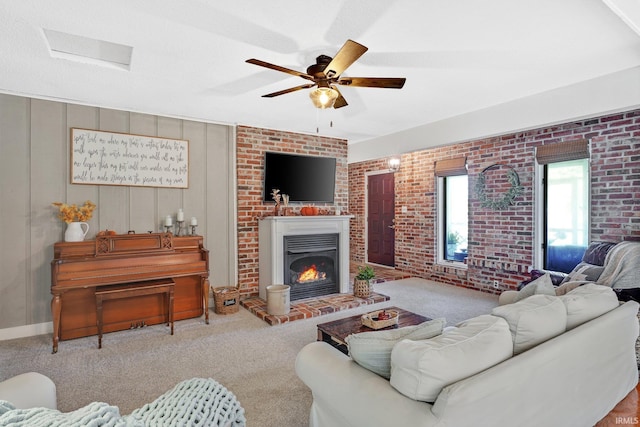 carpeted living room with ceiling fan and brick wall