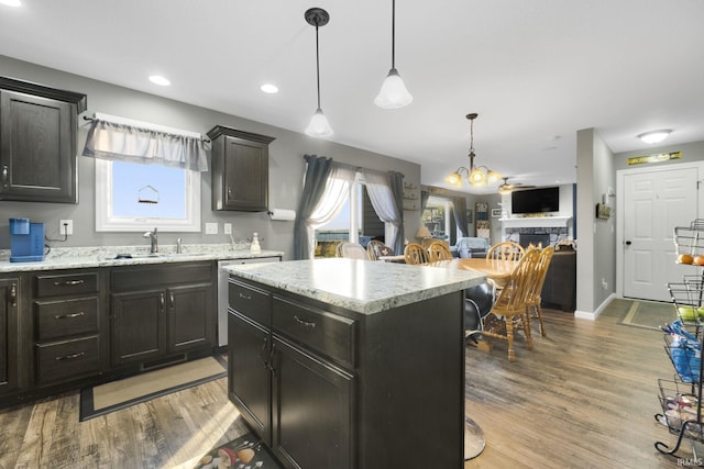 kitchen featuring sink, pendant lighting, a center island, a stone fireplace, and a breakfast bar area