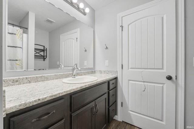 bathroom featuring hardwood / wood-style flooring, vanity, and a textured ceiling