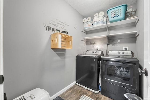 clothes washing area with washing machine and clothes dryer, a textured ceiling, and dark hardwood / wood-style floors