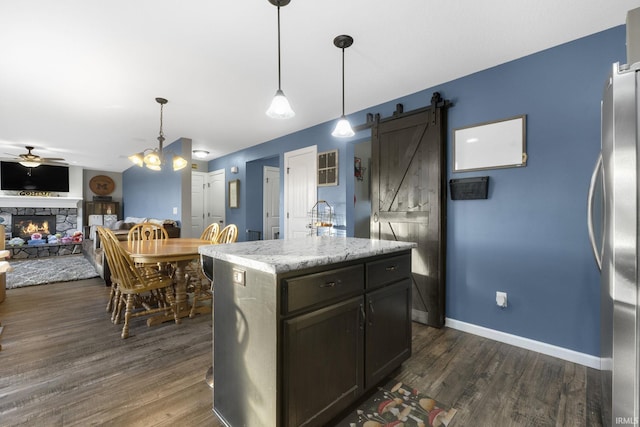 kitchen with ceiling fan, pendant lighting, a barn door, a kitchen island, and stainless steel refrigerator