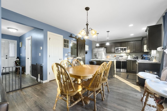 dining area featuring a barn door, dark hardwood / wood-style floors, an inviting chandelier, and sink