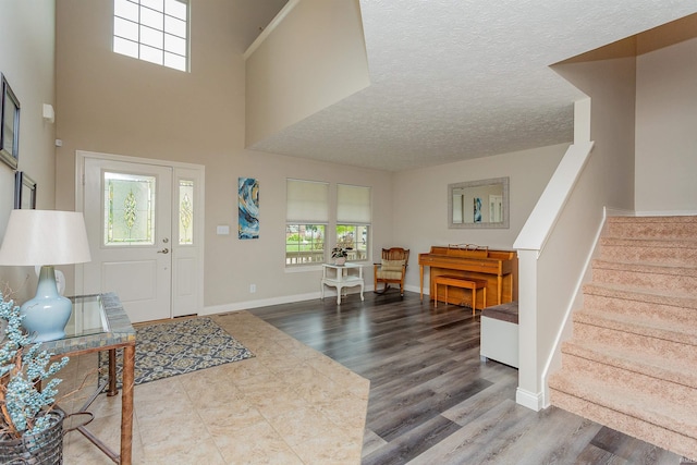 entryway featuring a towering ceiling, hardwood / wood-style floors, and a textured ceiling