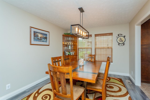 dining space featuring dark hardwood / wood-style flooring, a textured ceiling, and a chandelier