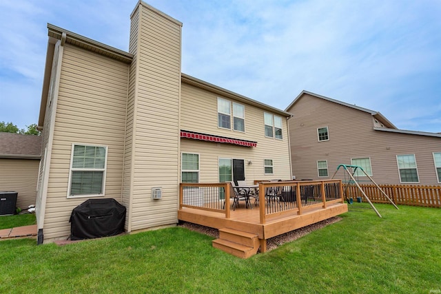 rear view of house with a wooden deck and a lawn