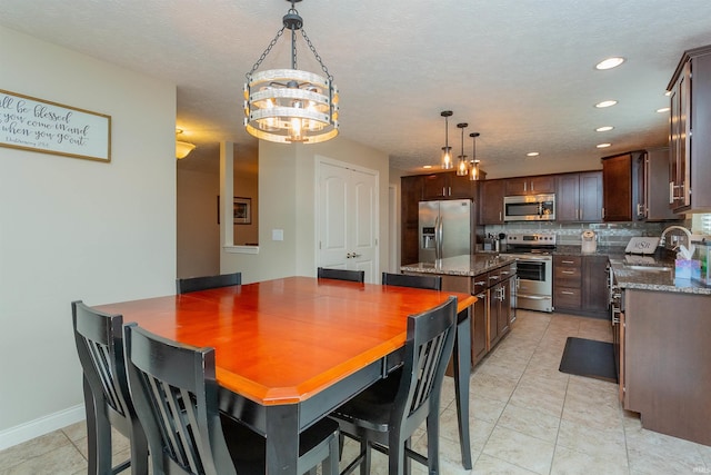 dining area with a textured ceiling, a notable chandelier, light tile patterned flooring, and sink