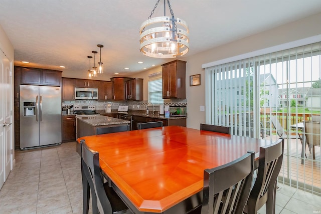 dining area featuring light tile patterned flooring, a notable chandelier, and sink