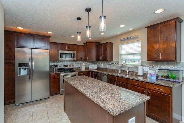 kitchen featuring a center island, sink, stainless steel appliances, pendant lighting, and decorative backsplash