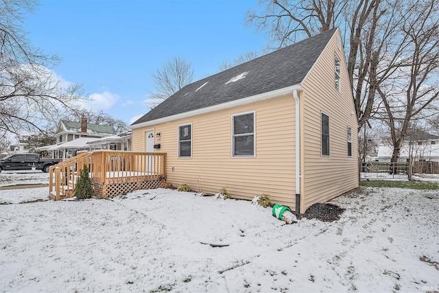 snow covered house featuring a wooden deck