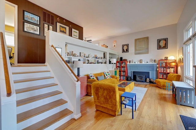 living room featuring plenty of natural light, light hardwood / wood-style floors, a wood stove, and ceiling fan