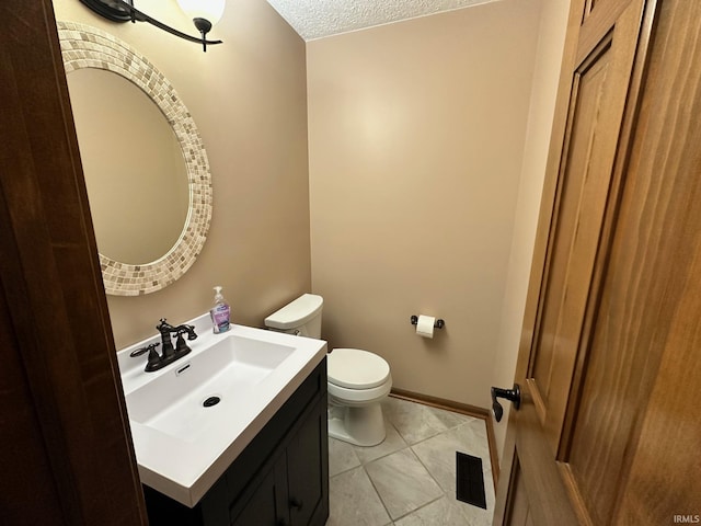 bathroom with tile patterned flooring, vanity, toilet, and a textured ceiling