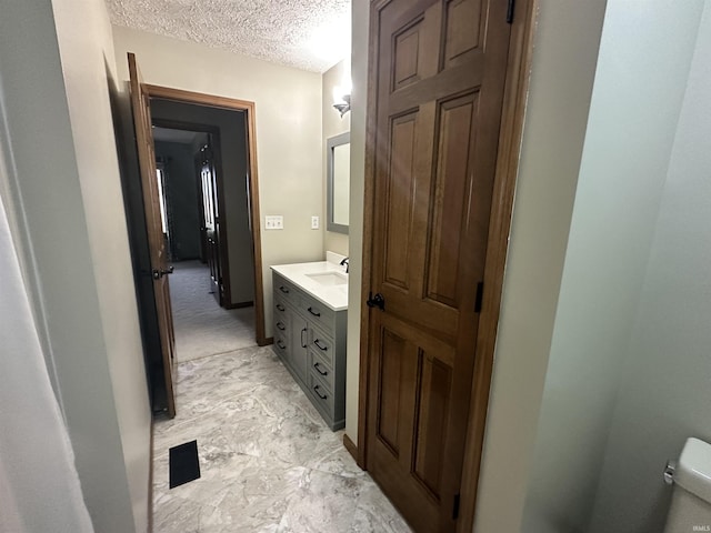 bathroom featuring vanity, toilet, and a textured ceiling