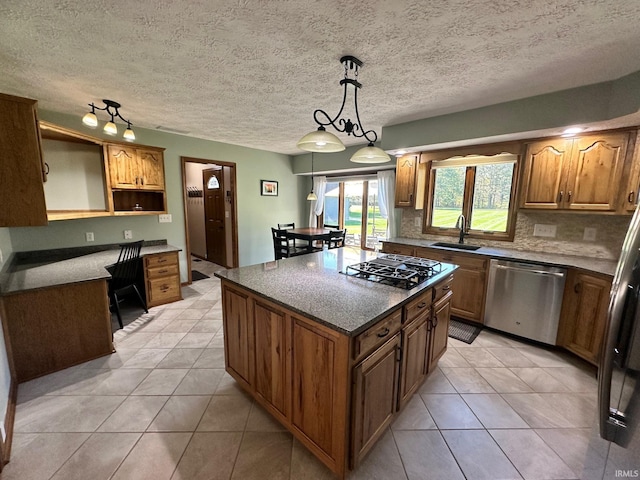 kitchen with sink, stainless steel appliances, light tile patterned floors, decorative light fixtures, and a kitchen island